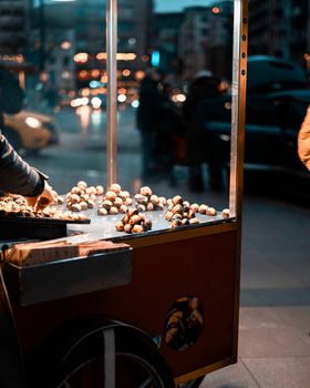 Vibrant urban scene of chestnut street vendor at night in İstanbul, Türkiye.