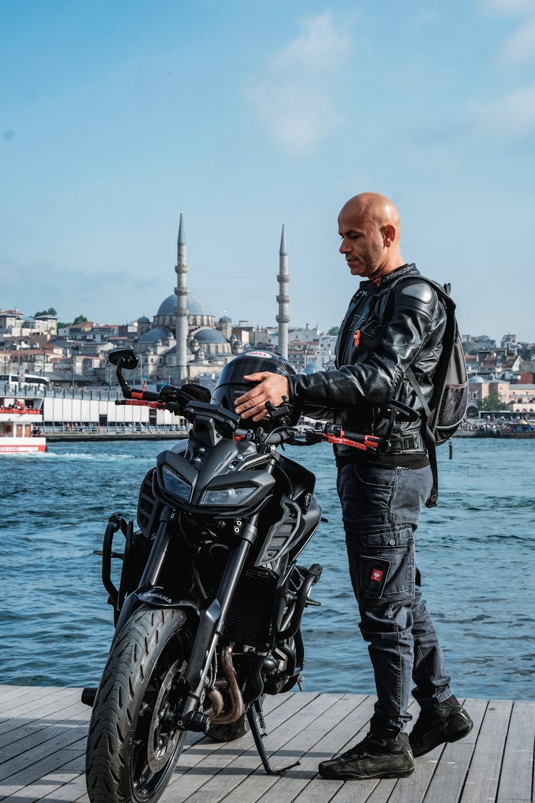 A Man In Black Leather Jacket Holding Black Helmet