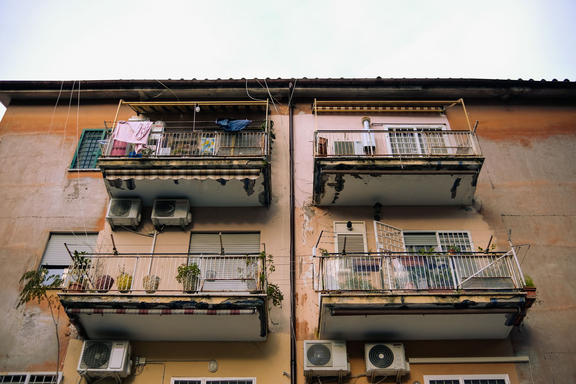 A rustic, weathered apartment building's exterior showing balconies and air conditioning units.