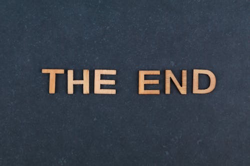 A Sign Saying "The End" Made from Wooden Letters Lying on Blue Background 