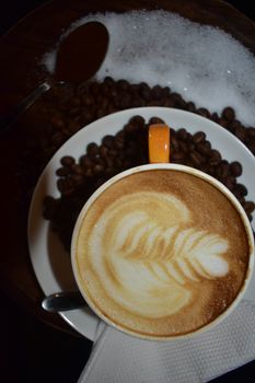 A latte with intricate latte art surrounded by coffee beans. Ideal for cafe-themed imagery.