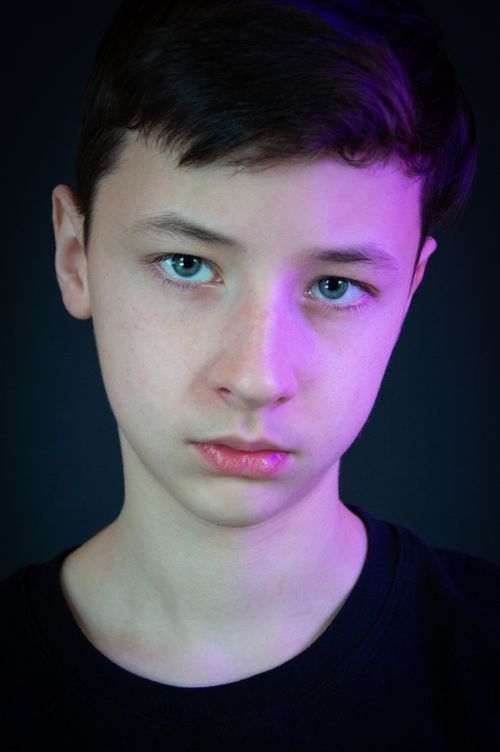 Free Portrait of a teenager in a studio setting with striking purple lighting. Stock Photo
