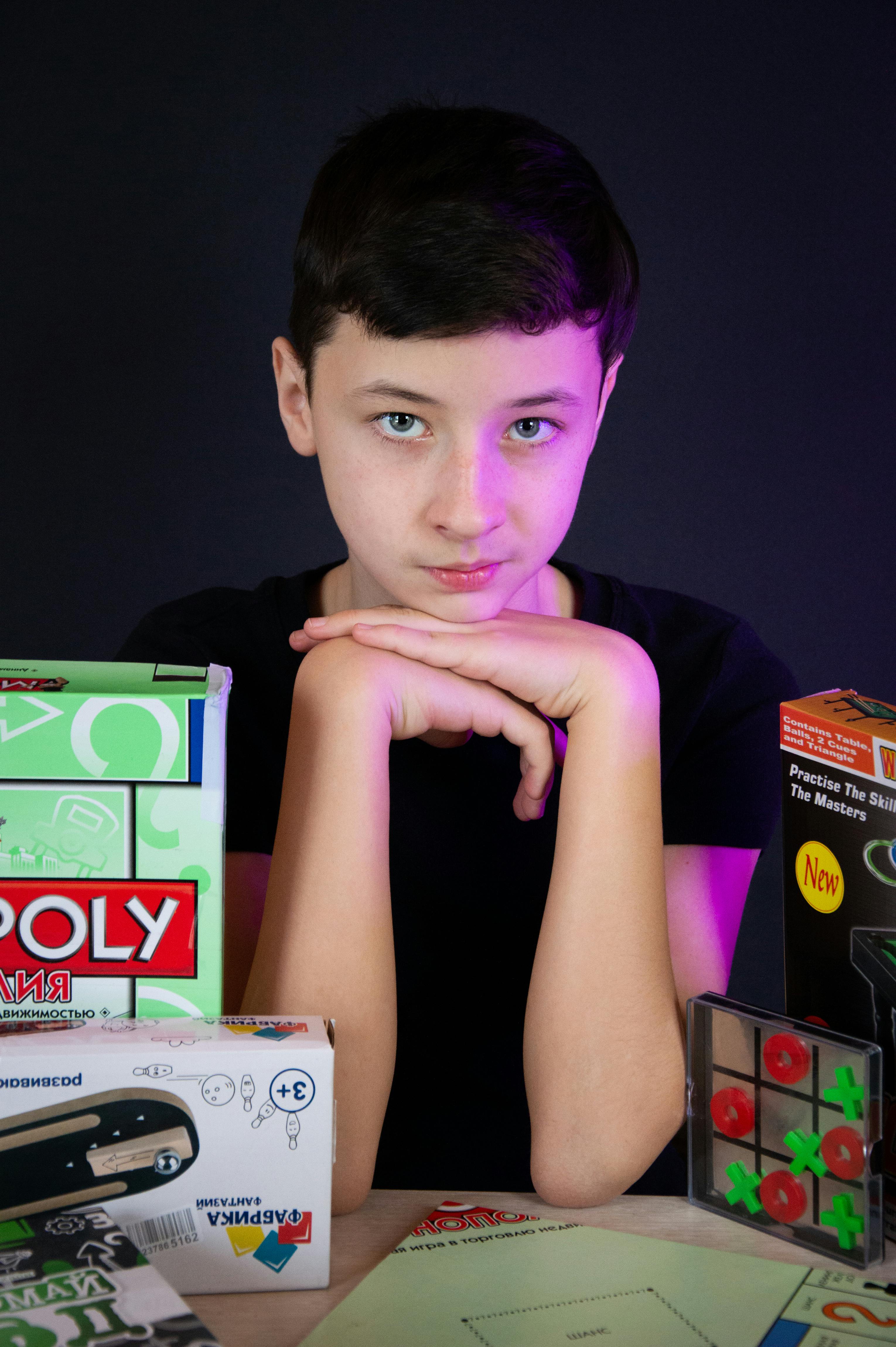 Boy Sitting Among Board Games · Free Stock Photo