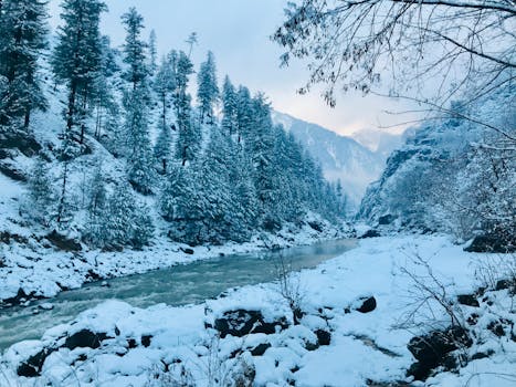 Breathtaking winter scene of snow-covered Kaghan Valley with river and mountains.