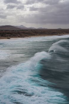 Powerful ocean waves crashing on the rugged coast of Spain under a moody sky.