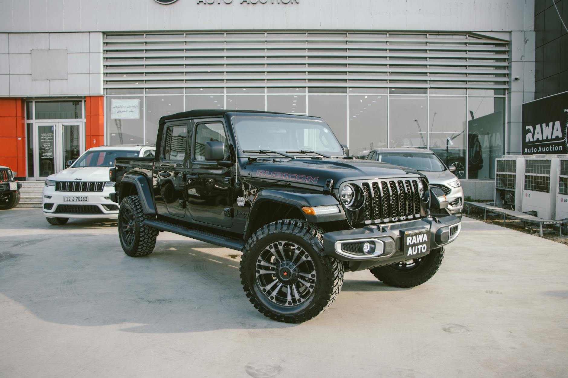 Black Jeep Gladiator Rubicon showcased outside RAWA Auto Auction dealership.