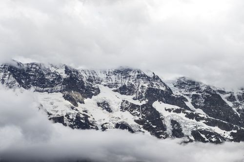 Free Scenic view of snow-covered mountains in Schwyz, Switzerland, obscured by clouds on a winter day. Perfect for travel and nature themes. Stock Photo