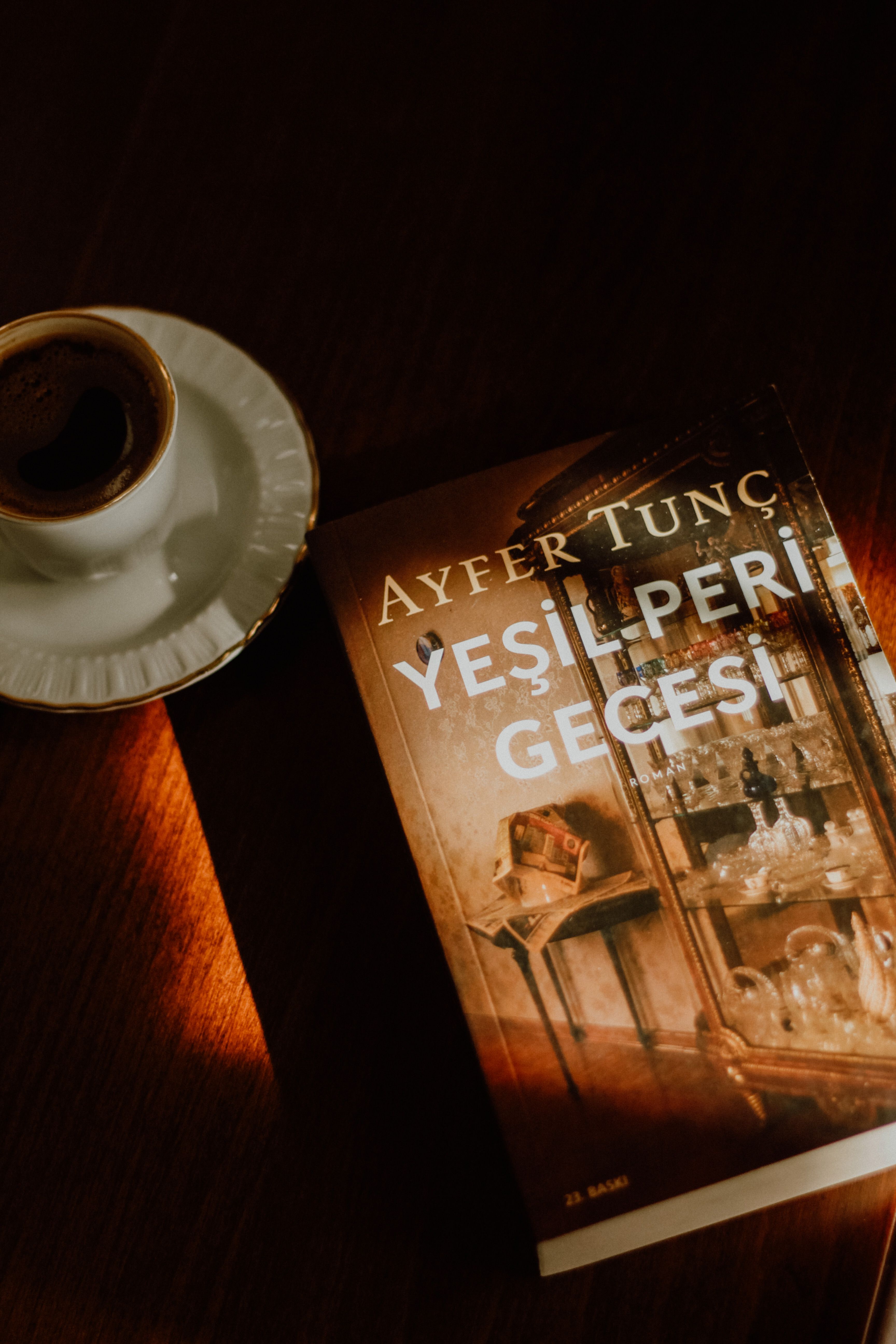 Warm lighting highlights a book and coffee, creating a cozy and inviting scene.