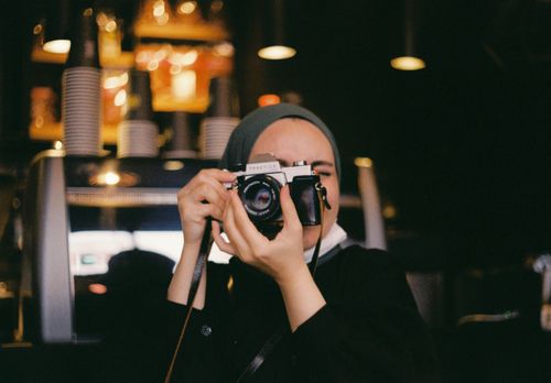 Free Young woman with analog camera in a cozy İstanbul café setting, capturing a moment of creativity. Stock Photo