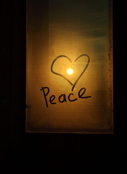 Free A heart and the word peace drawn on a glass panel with the sunset in the background. Stock Photo