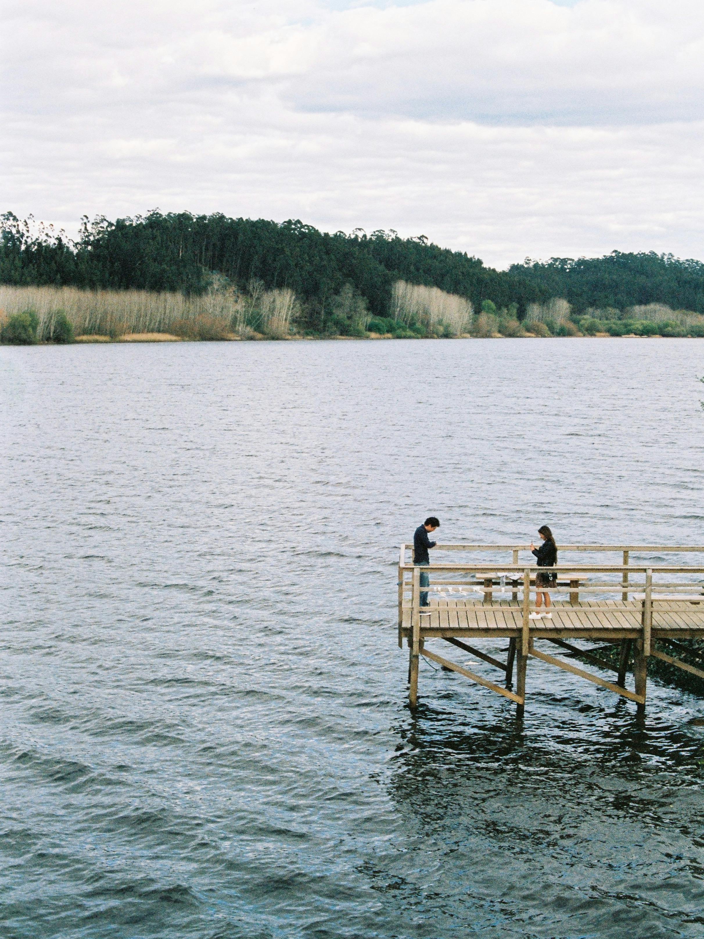 A serene couple enjoying a peaceful moment on a wooden pier at a lake in Aveiro, Portugal.