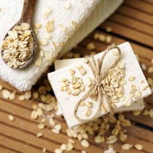 Unbranded oatmeal soap bar tied with twine beside a folded towel on warm wood — photo by Erly Morales on Pexels