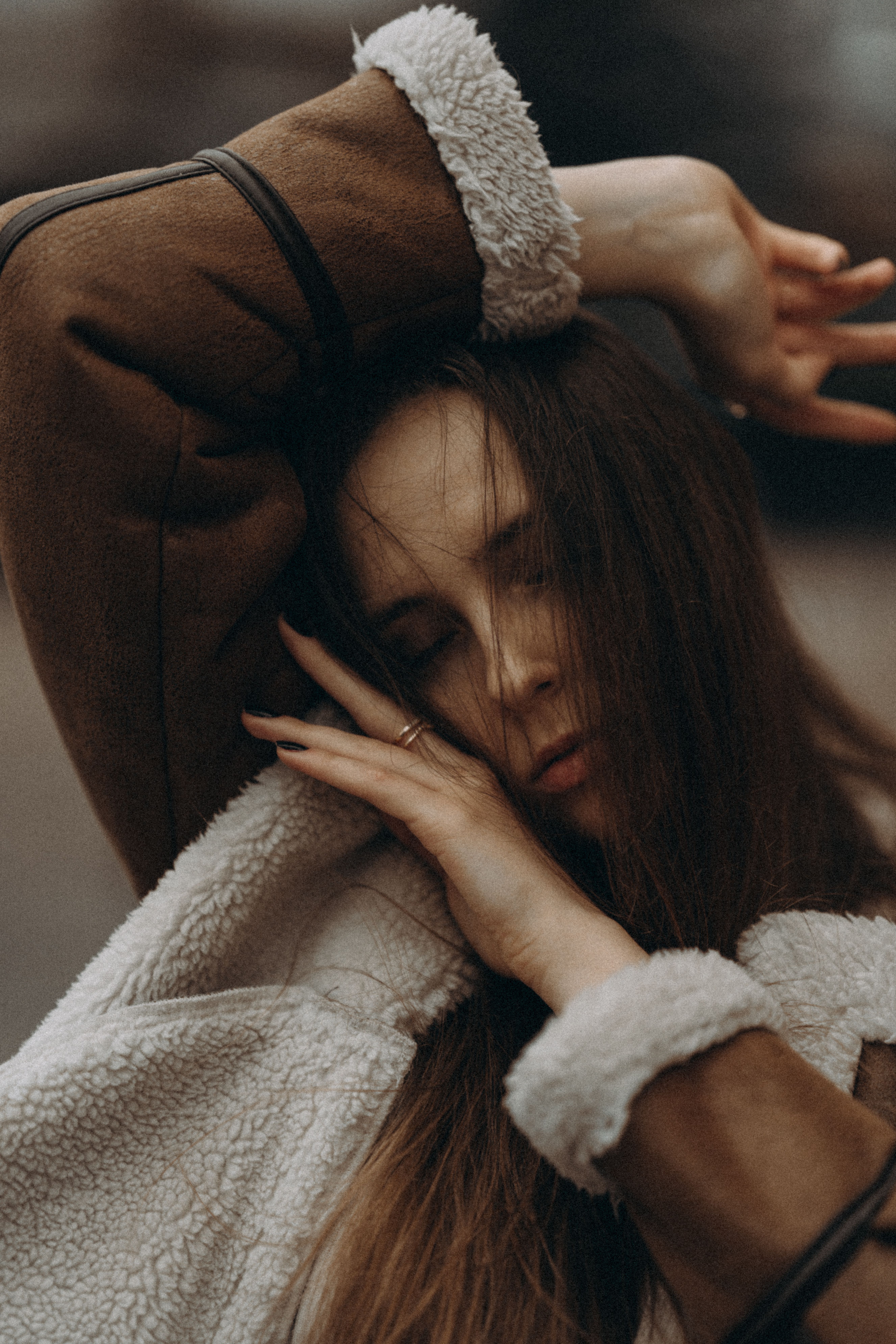 Young woman with eyes closed, wearing a warm winter jacket, poses gracefully outdoors.