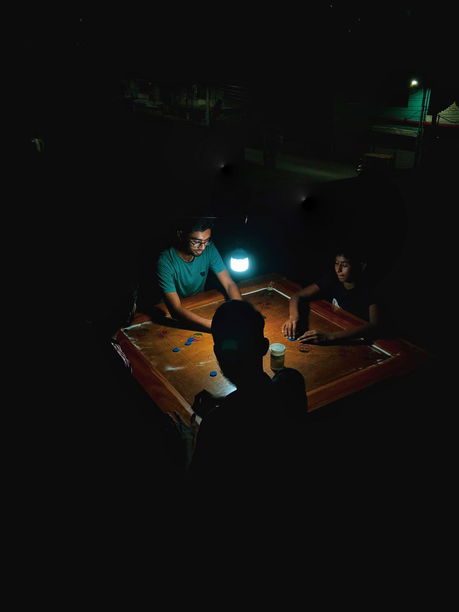 Four friends playing carrom at night under a single lamp
