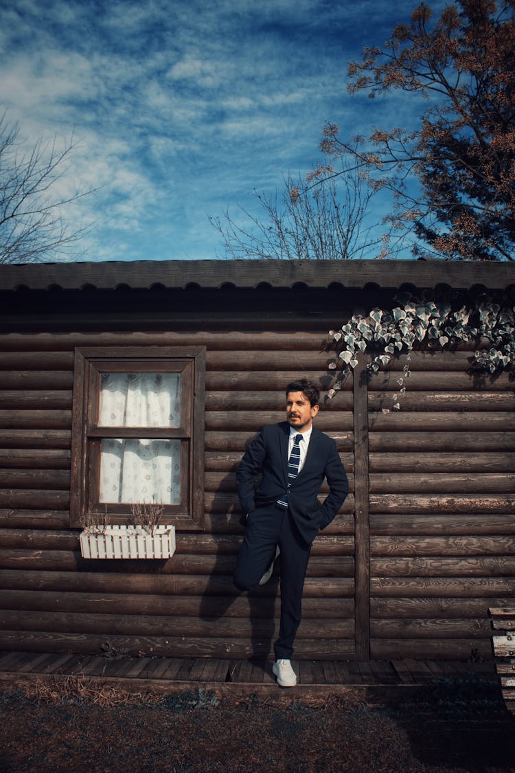 Man In Suit Posing By Wooden House