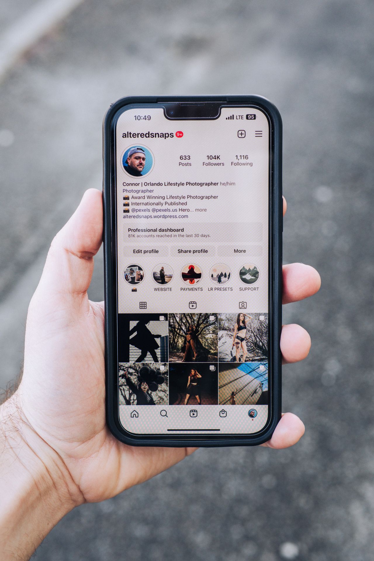 Mão segurando celular com perfil do Instagram na tela