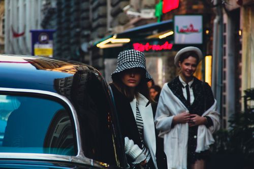 Free Chic urban fashion with women in hats next to a classic car on a bustling city street. Stock Photo