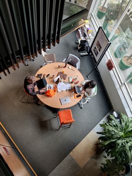 Top view of professionals collaborating in a modern Gurugram office with laptops and coffee.