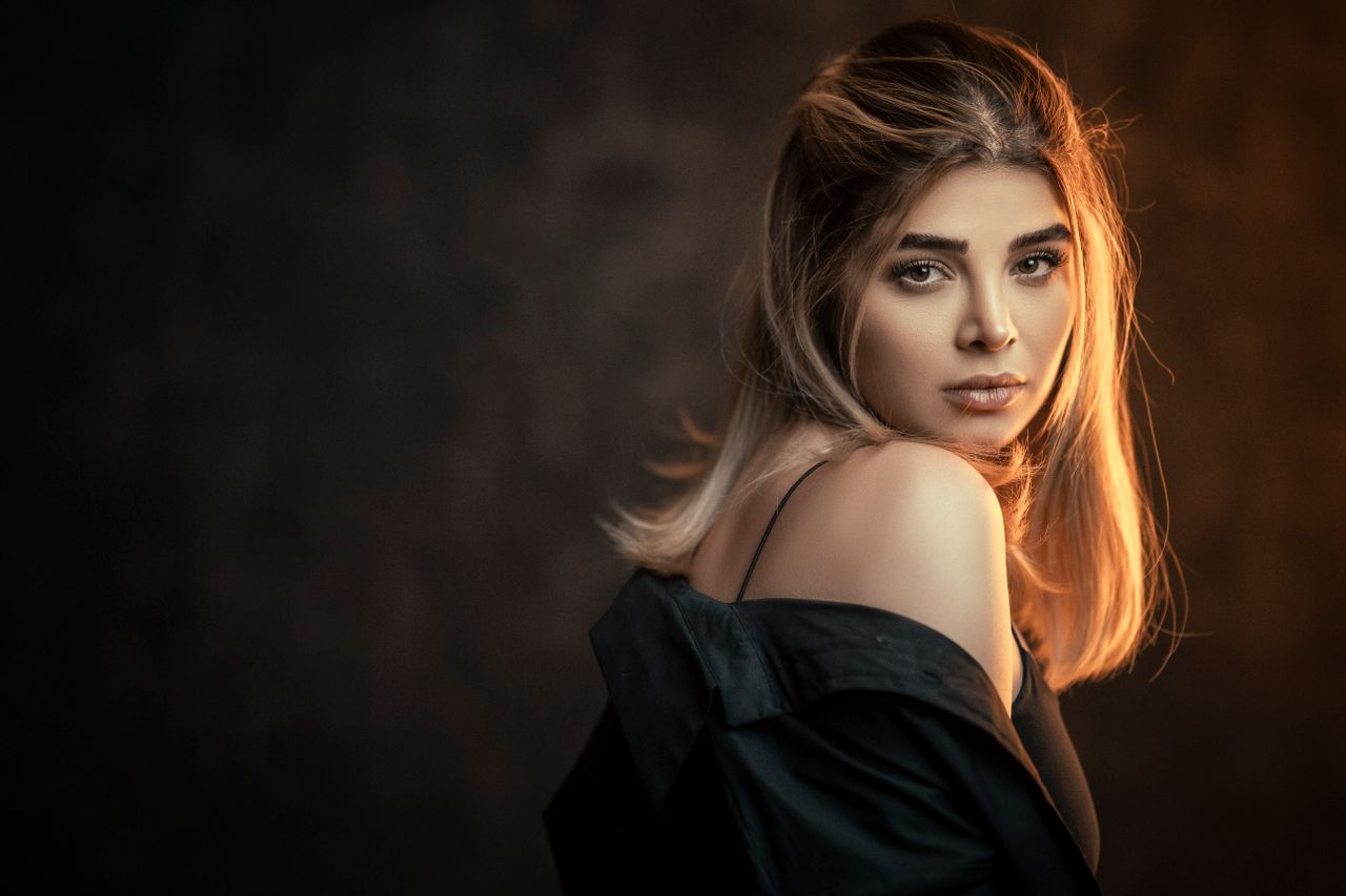 glamorous woman posing in a studio with a dark background and elegant