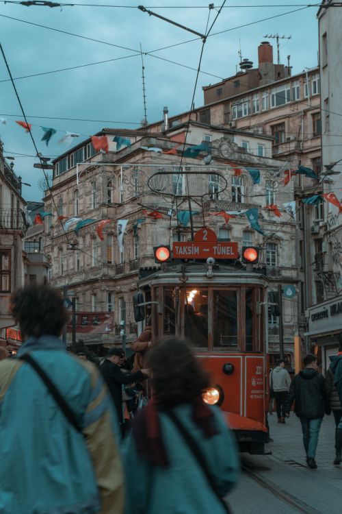 Free A classic red tram navigates through a bustling street in Istanbul under festive flags. Stock Photo