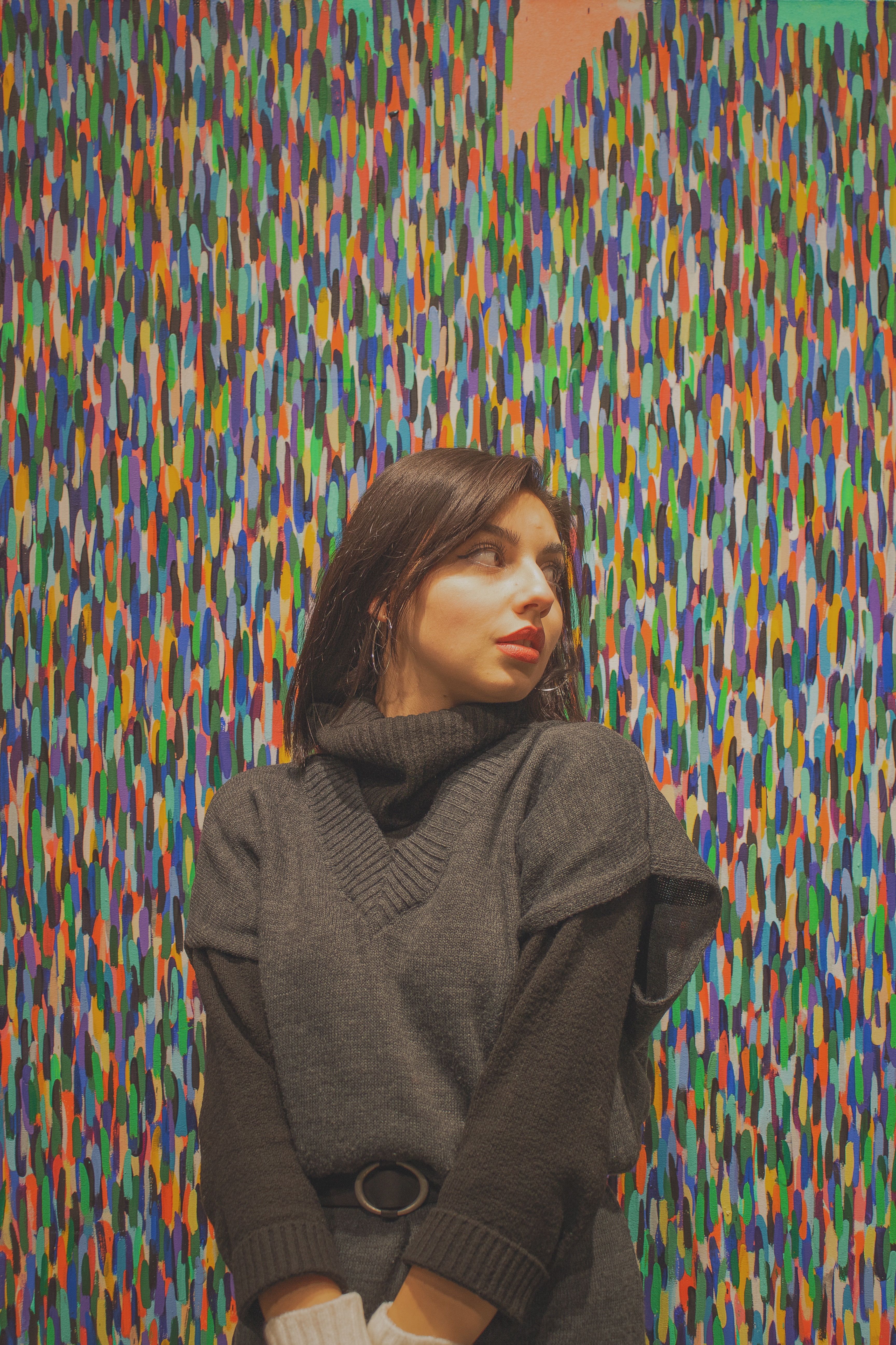 Stylish woman poses in knitwear against a vibrant and colorful abstract background in Ankara, Türkiye.