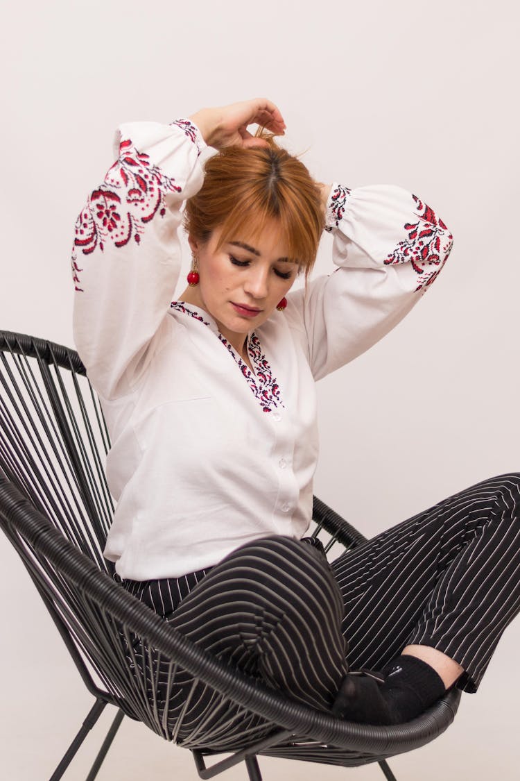 Woman In Embroidered Blouse Sitting In Chair In Studio