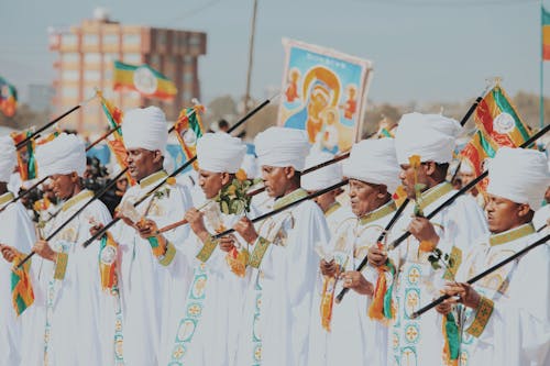 Men in White Gowns and Turbans Holding Flags during a Religious Ceremony 