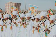 Ethiopian ritual in Addis Ababa with men in white gowns and turbans holding religious items.