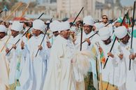 Men in traditional Ethiopian attire participate in a vibrant outdoor parade celebrating culture.