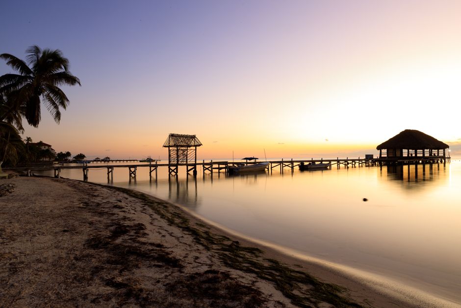 Peaceful sunrise view of a wooden pier extending into the serene ocean waters at San Pedro, Belize.