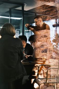 A group of professionals collaborate in a reflective glass office setting, capturing teamwork creativity.