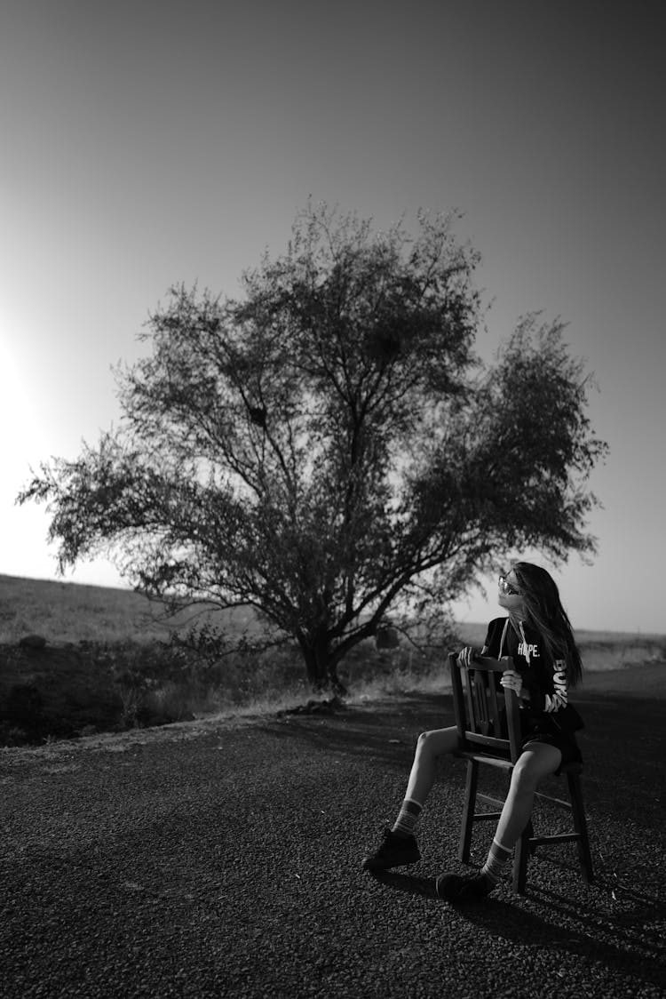 Woman Sitting Backward On Chair In Rural Landscape