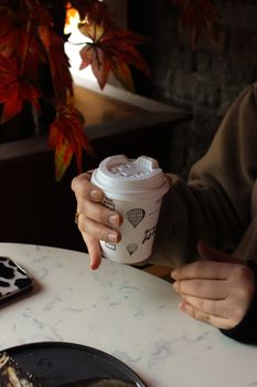 Enjoying a cozy coffee indoors with autumn leaves and warm lighting.