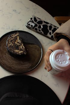 A cozy coffee break featuring a rich chocolate cake slice and a trendy phone case.