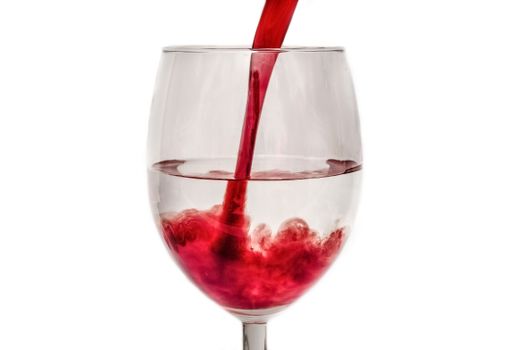 Close-up of red wine being poured into a clear glass against a white background.