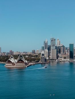 Aerial view of Sydney Opera House with the city skyline in the backdrop under a clear blue sky.