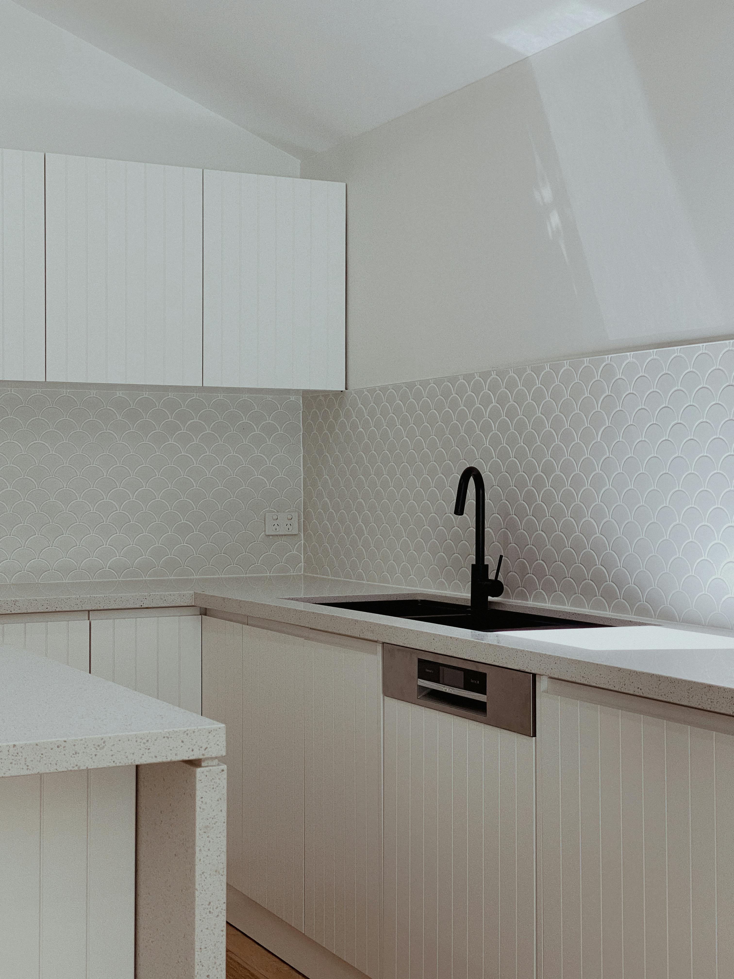 Minimalist kitchen featuring white cabinetry and modern black faucet.