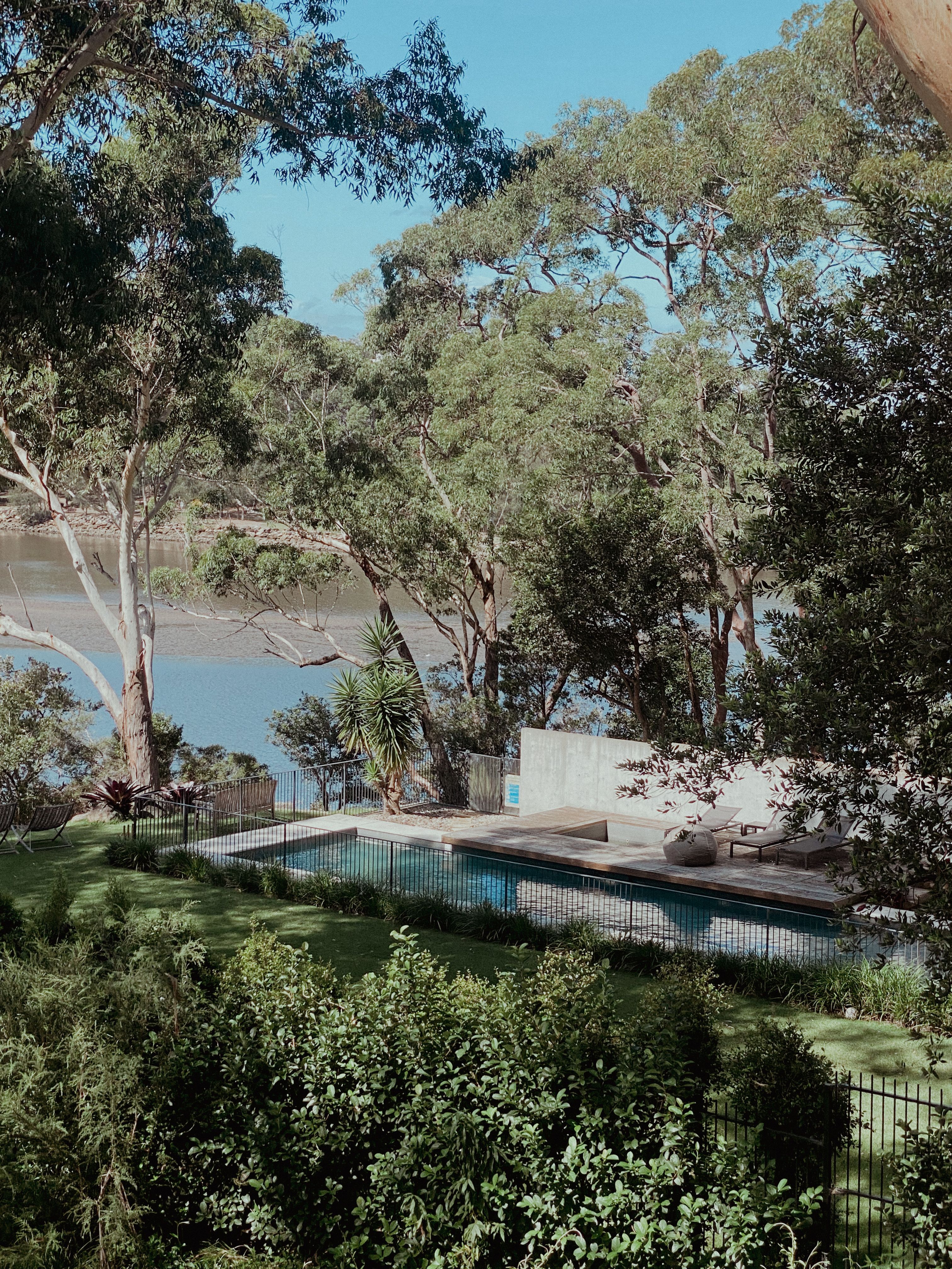 View of a Swimming Pool in the Yard with Trees near a Body of Water ...