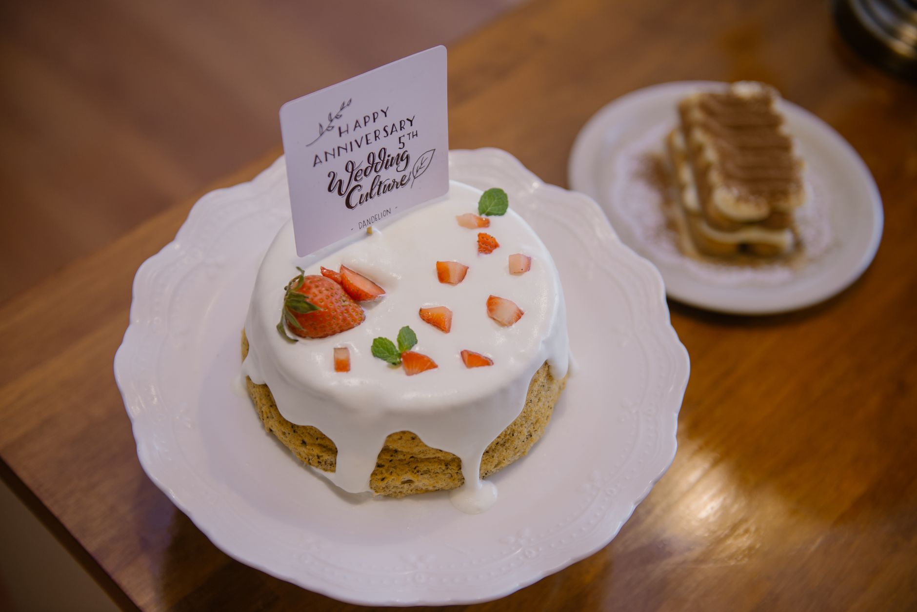 A beautiful anniversary cake with strawberries and cream on a decorative plate.