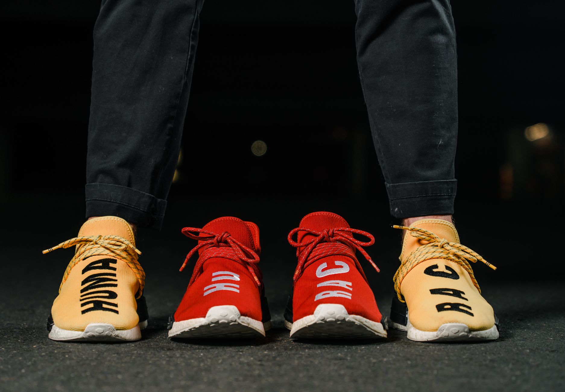 Vibrant red and yellow sneakers with bold text capture attention in a city night setting.