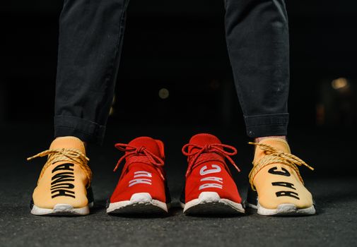 Vibrant red and yellow sneakers with bold text capture attention in a city night setting.