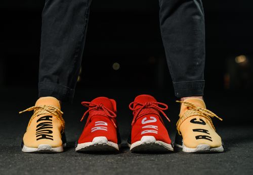 Free Vibrant red and yellow sneakers with bold text capture attention in a city night setting. Stock Photo