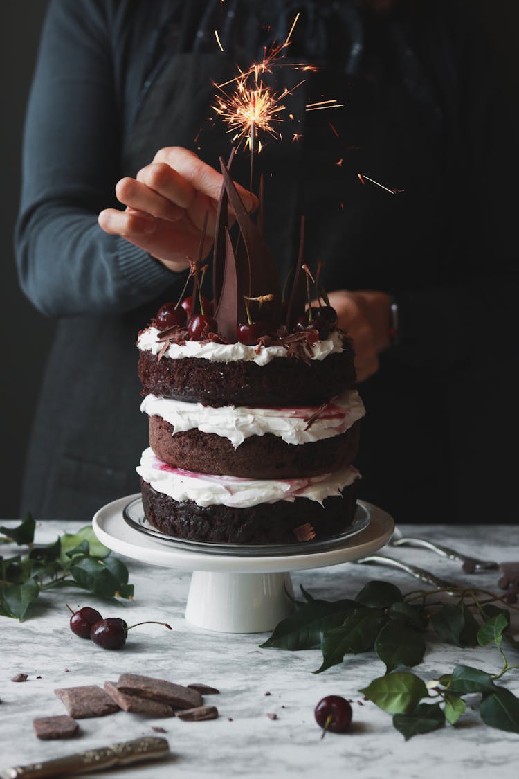 Woman Putting Candle On Birthday Cake