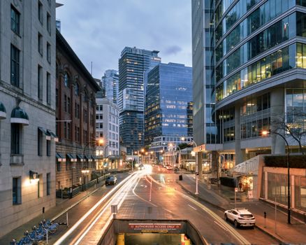 Dynamic city street with light trails and skyscrapers at dusk, showcasing urban life.