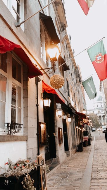 A lively street in Old Montreal adorned with flags and festive lights, capturing a European architectural charm.