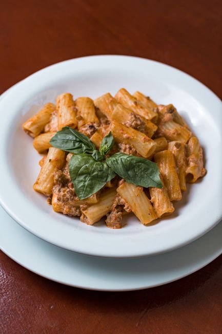 A plate of pasta with tomato sauce and fresh herbs garnish