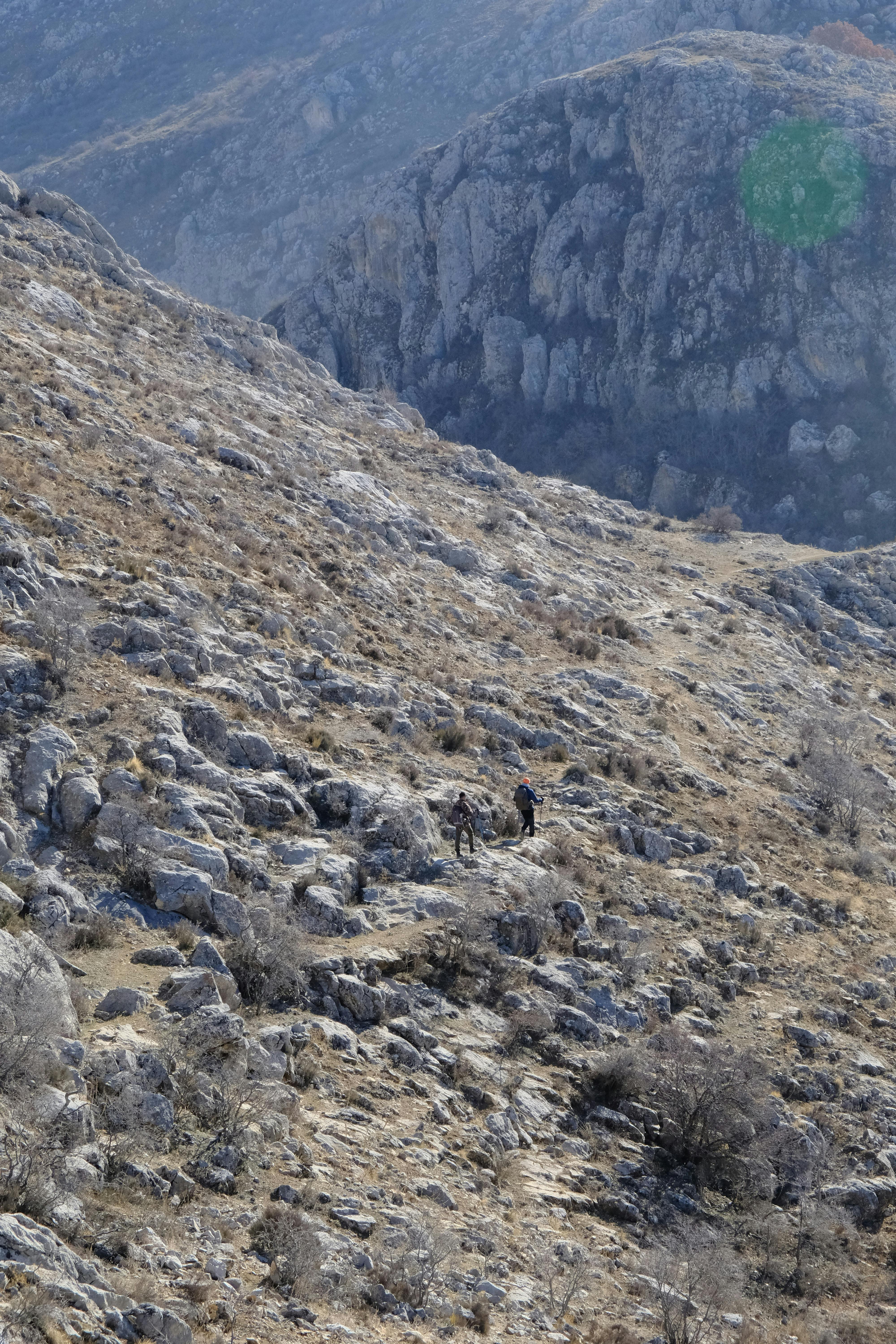 Two hikers trekking across a rugged rocky mountain landscape, showcasing natural beauty.
