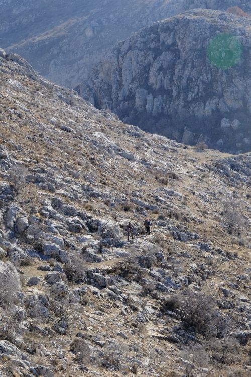 Free Two hikers trekking across a rugged rocky mountain landscape, showcasing natural beauty. Stock Photo