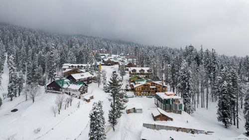 Free Aerial view of a snow-covered village in Gulmarg, surrounded by pine forests. Stock Photo