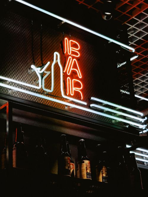 Free Neon bar sign illuminating bottles in a cozy Kyiv bar setting, showcasing urban nightlife. Stock Photo